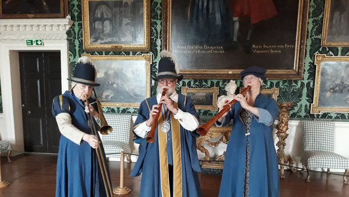 3 people dress in blue robes playing instruments in Temple Newsam