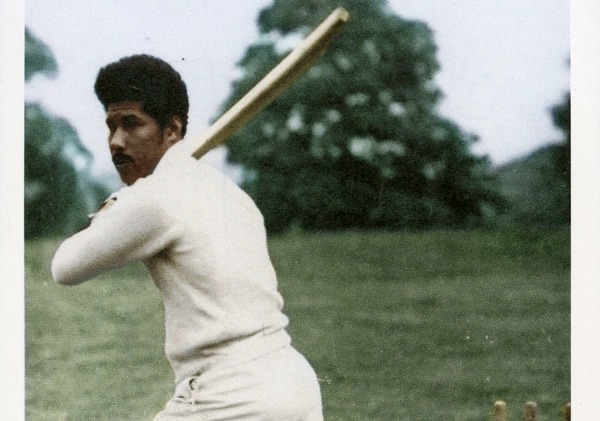 Man wearing cricket gear swinging the bat over his shoulder