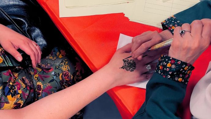 Someone painting henna onto another persons hand.