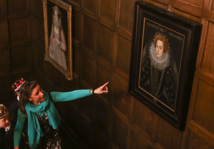 a teacher and students looking at a portrait of Queen Elizabeth