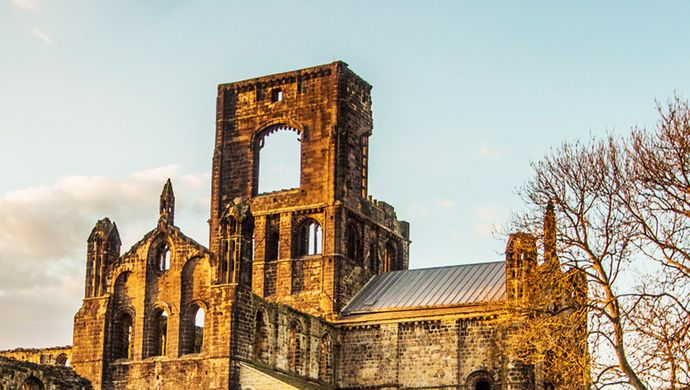 The ruins of Kirkstall Abbey with an evening glow on the stones
