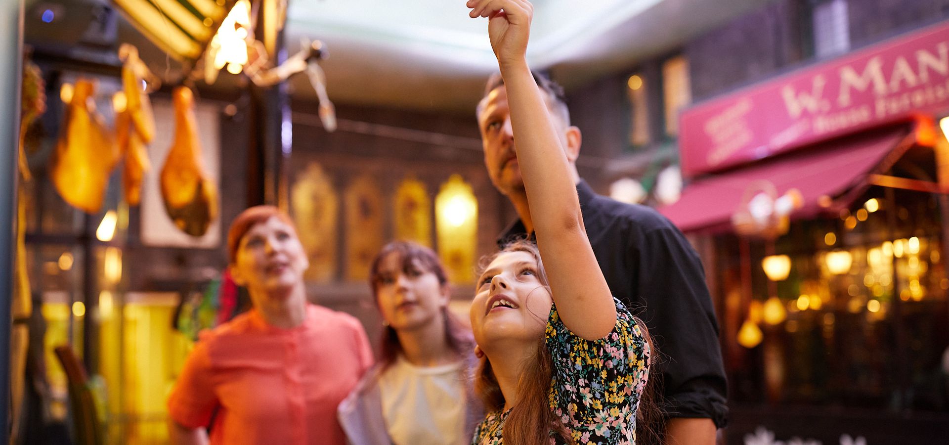 Two adults and two children looking at hanging objects in Abbey House Museum