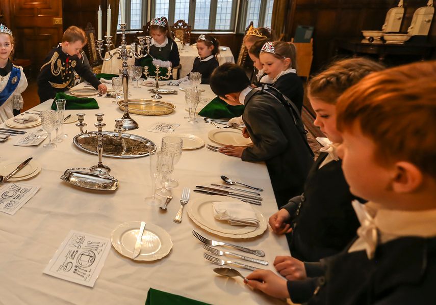 A group of students in victorian attire around a dressed table in Temple Newsam