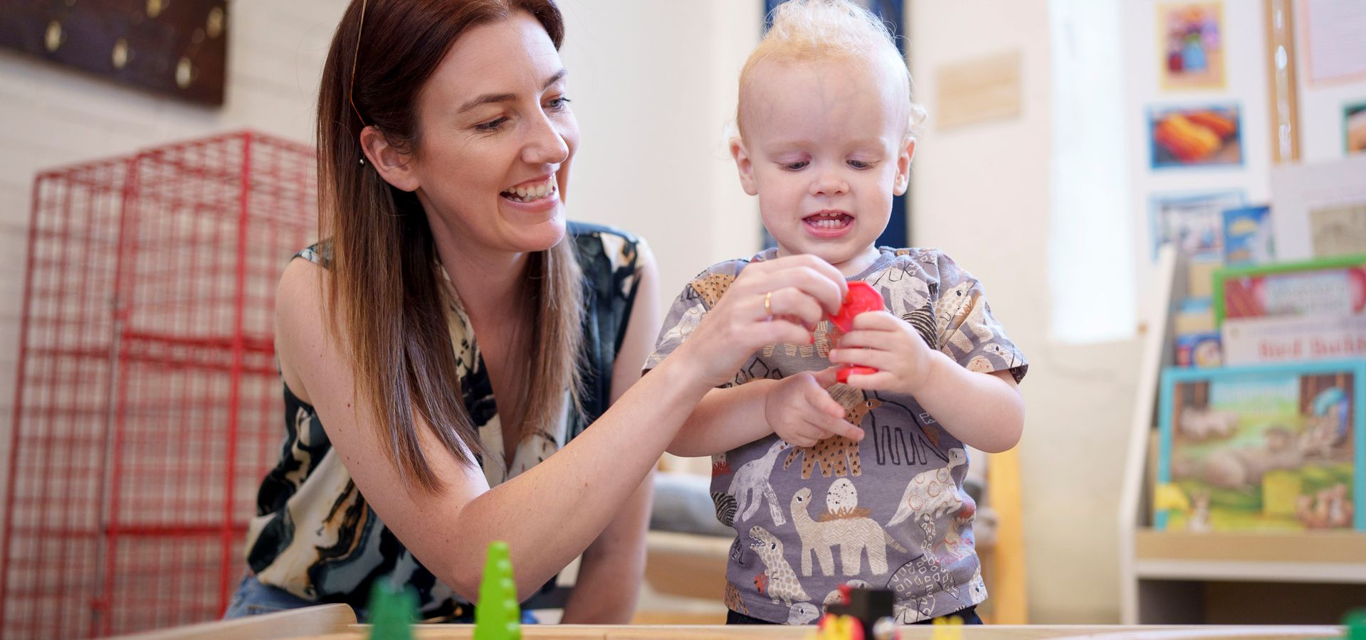 a toddler and adult playing with a toy train track