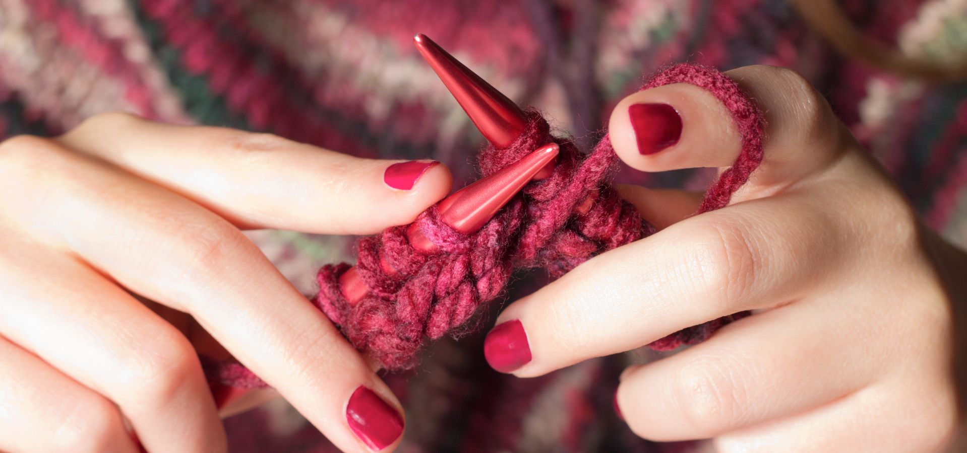 a person knitting with red wool