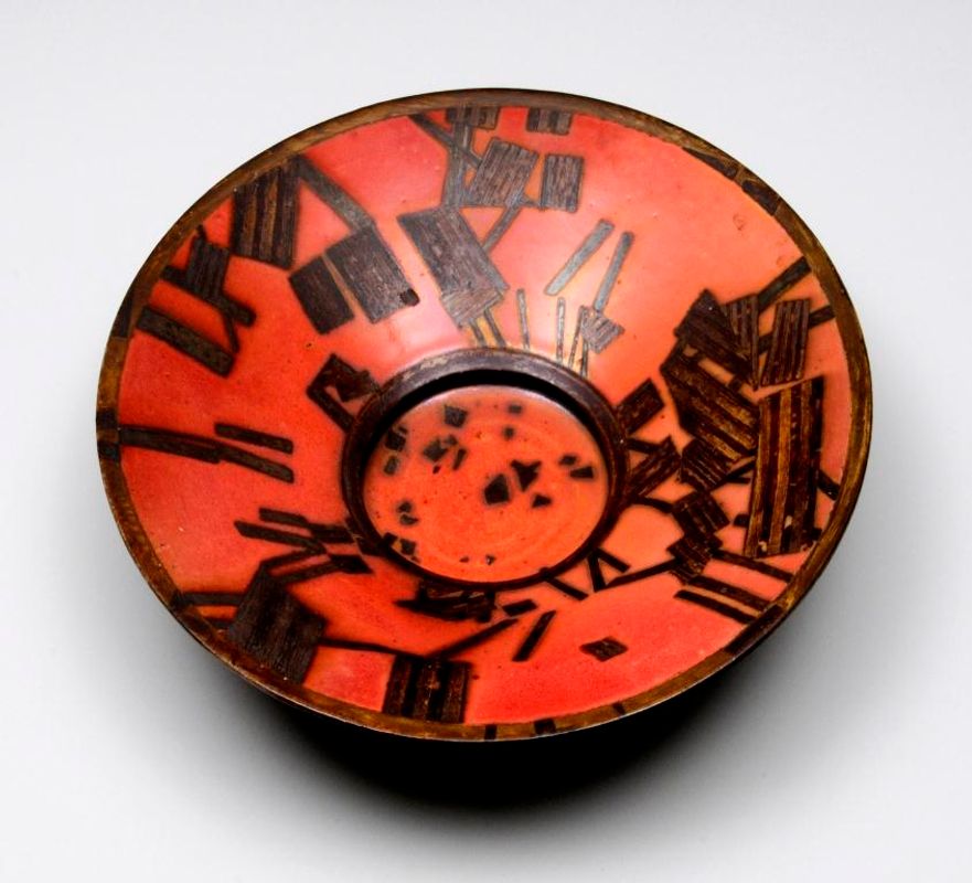 The inside of a red bowl with a black pattern on