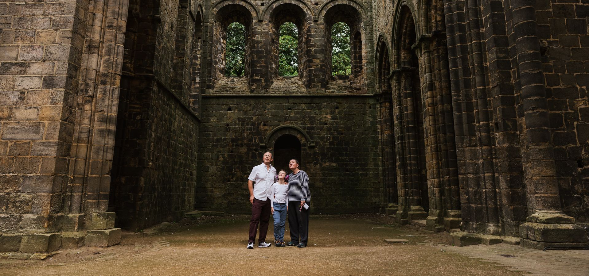 two adults and a child looking up at the ruins inside Kirkstall Abbey