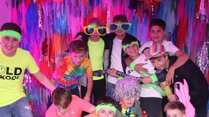 A group of children posing with fun props and wearing neon clothing