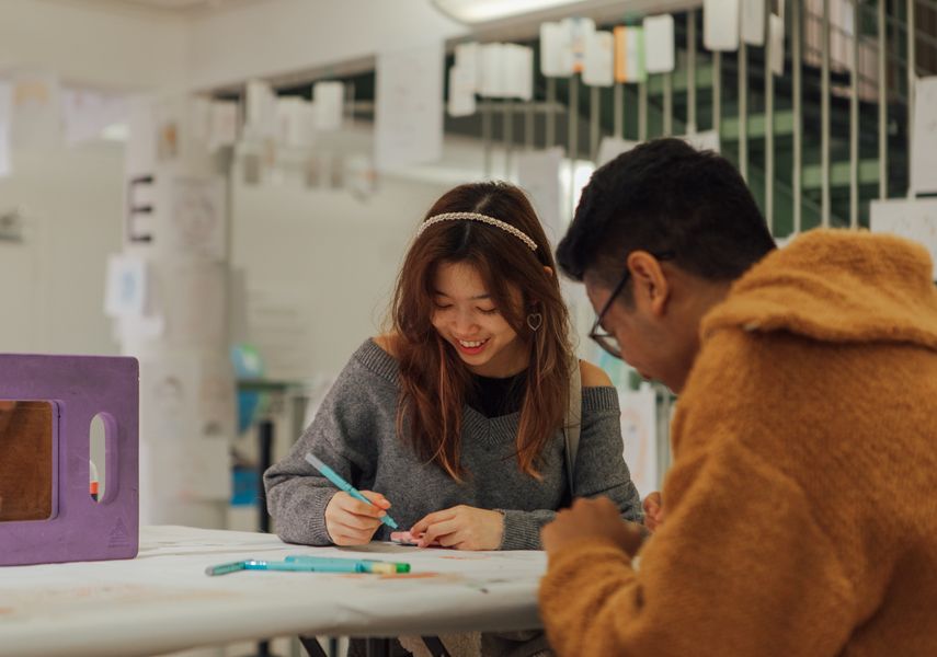 Two people draw at a table