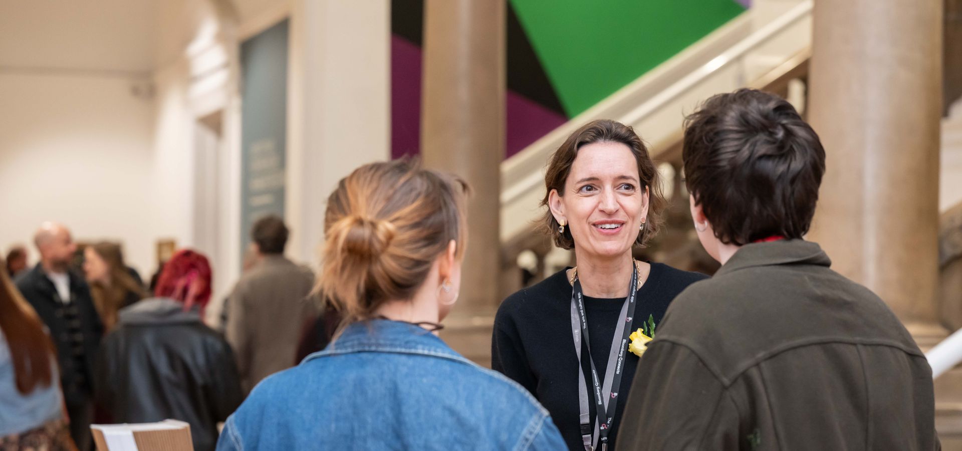 A member of staff welcome 2 visitors at Leeds Art Gallery