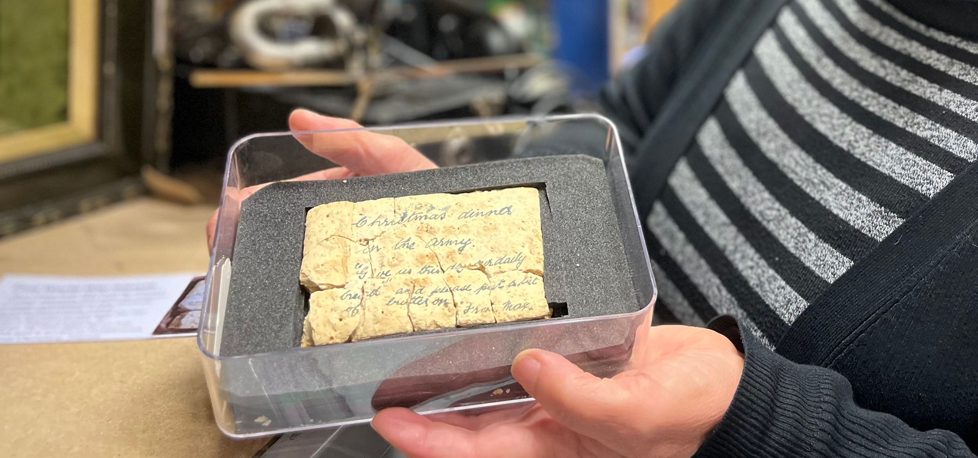 Social History Curator holding a biscuit in a case with a Christmas message on it 