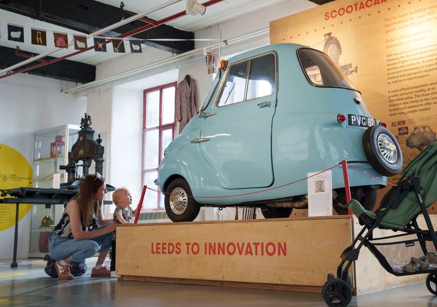 An adult and toddler looking at a scootercar at Leeds Industrial Museum