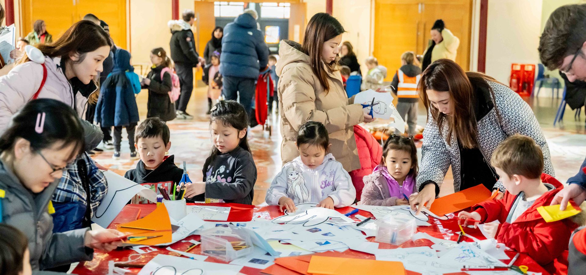 A group of adults and children doing craft activity around a table