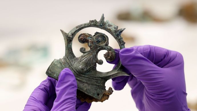 gloved hands holding an ornate iron buckle