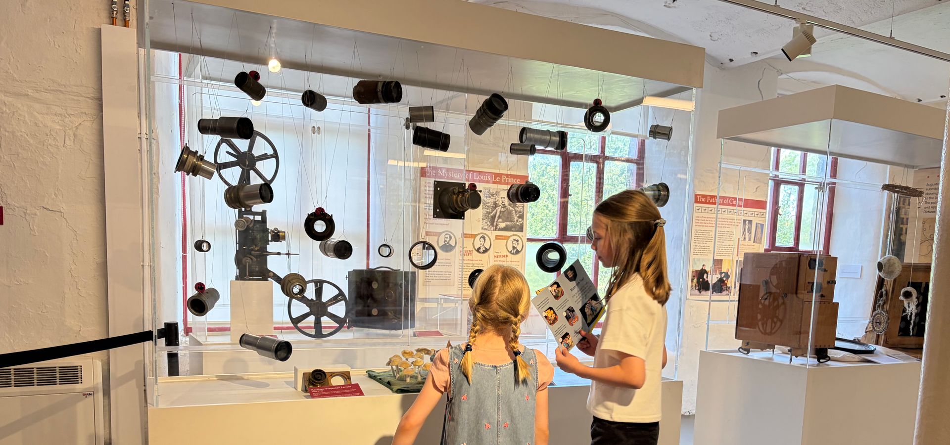 two girls looking at hung up camera parts on display