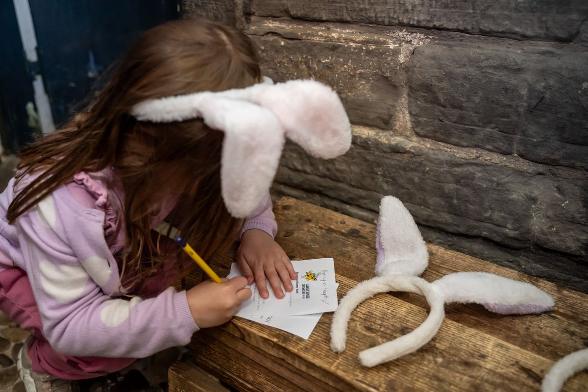 A girl writing on a piece of paper on a bench, wearing bunny ears