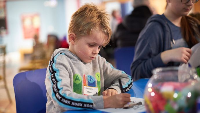 a young boy doing crafts at a table
