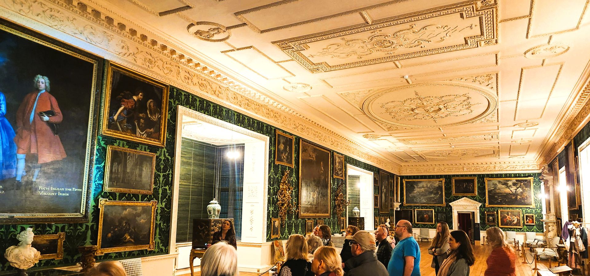 A group of people walking through a large room in Temple Newsam House