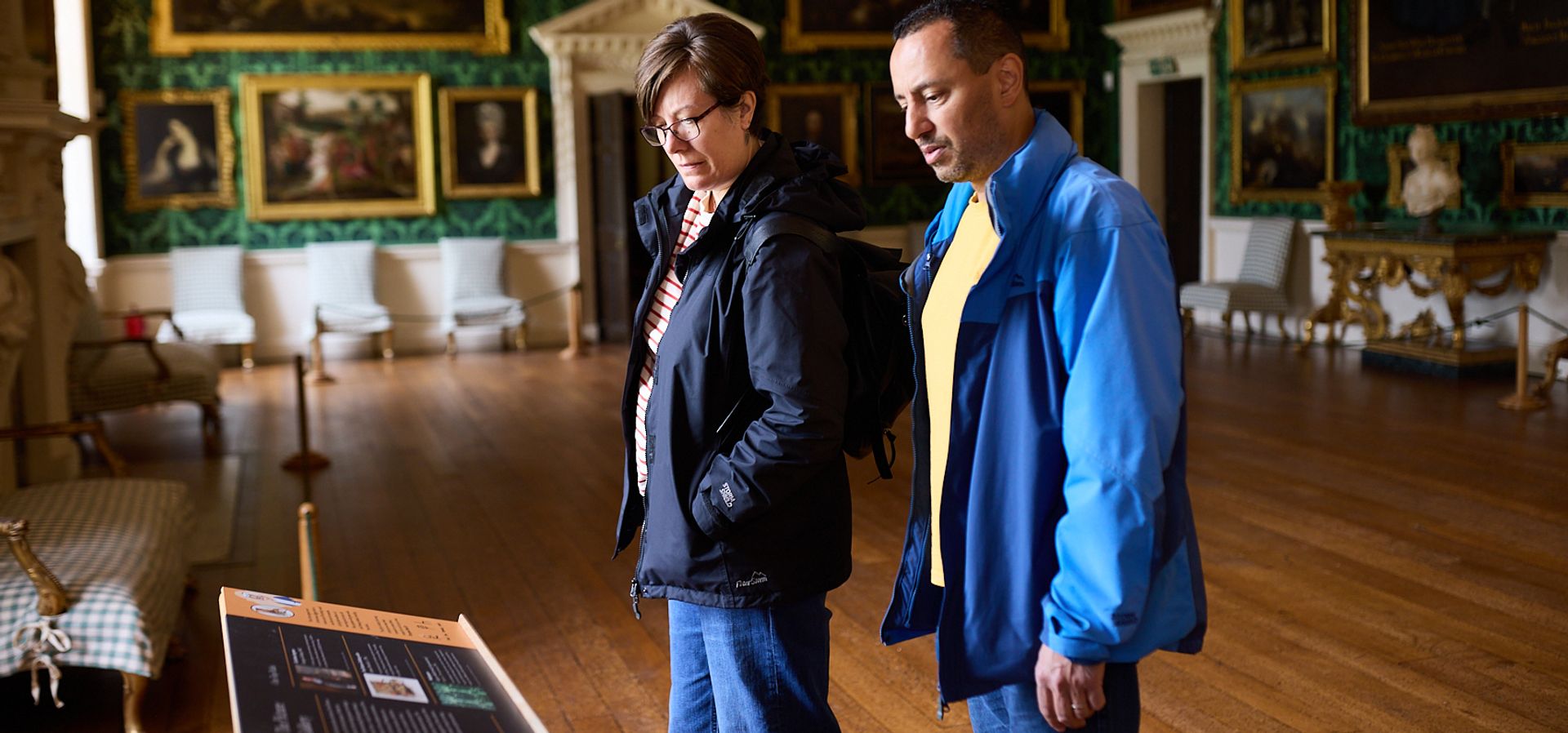 Two adults looking at a display board in the picture gallery in temple newsam