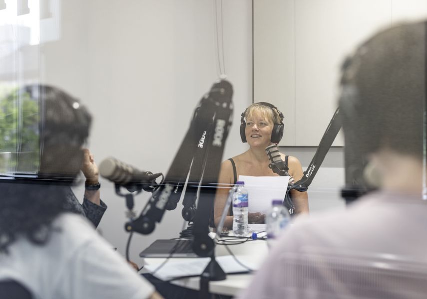 Abigail Harrison Moore speaking to members with headphones and speakers creating a podcast