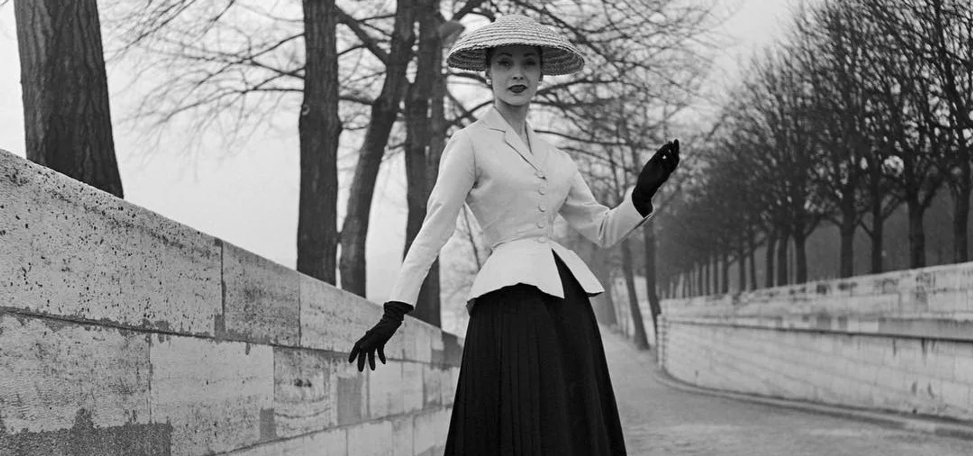 Women dressed in a hat, blouse, black gloves and a black midi skirt