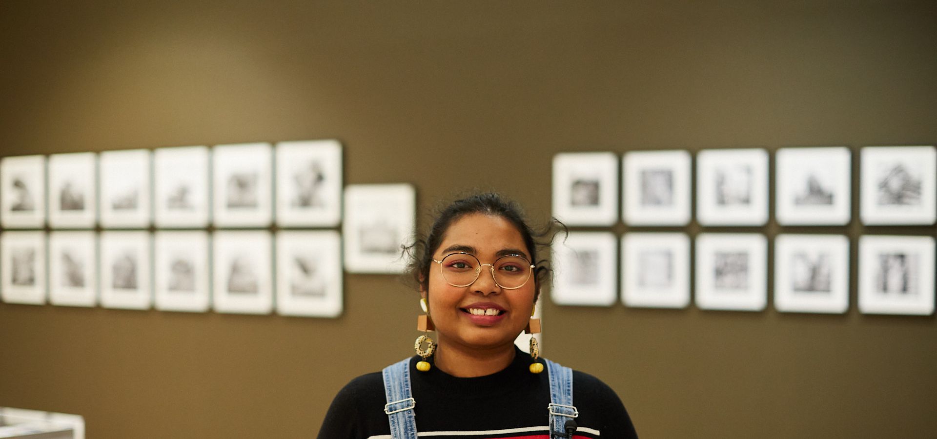 A young adult stood in front of a gallery wall