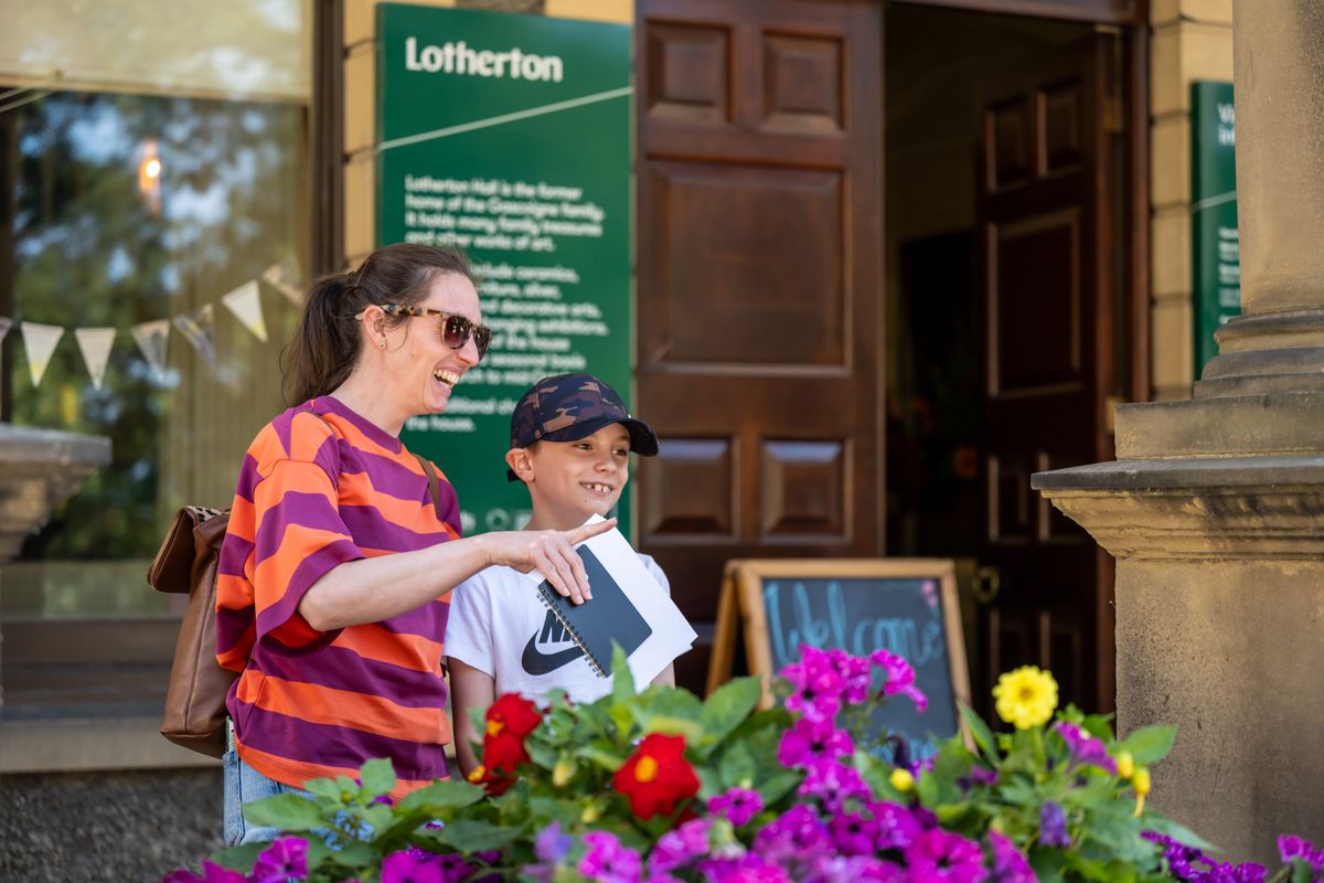 An adult and child looking at something out side of a heritage house