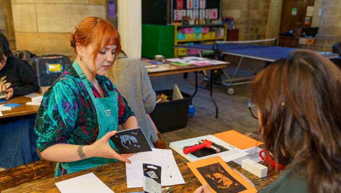 Two people sat at a table making zines