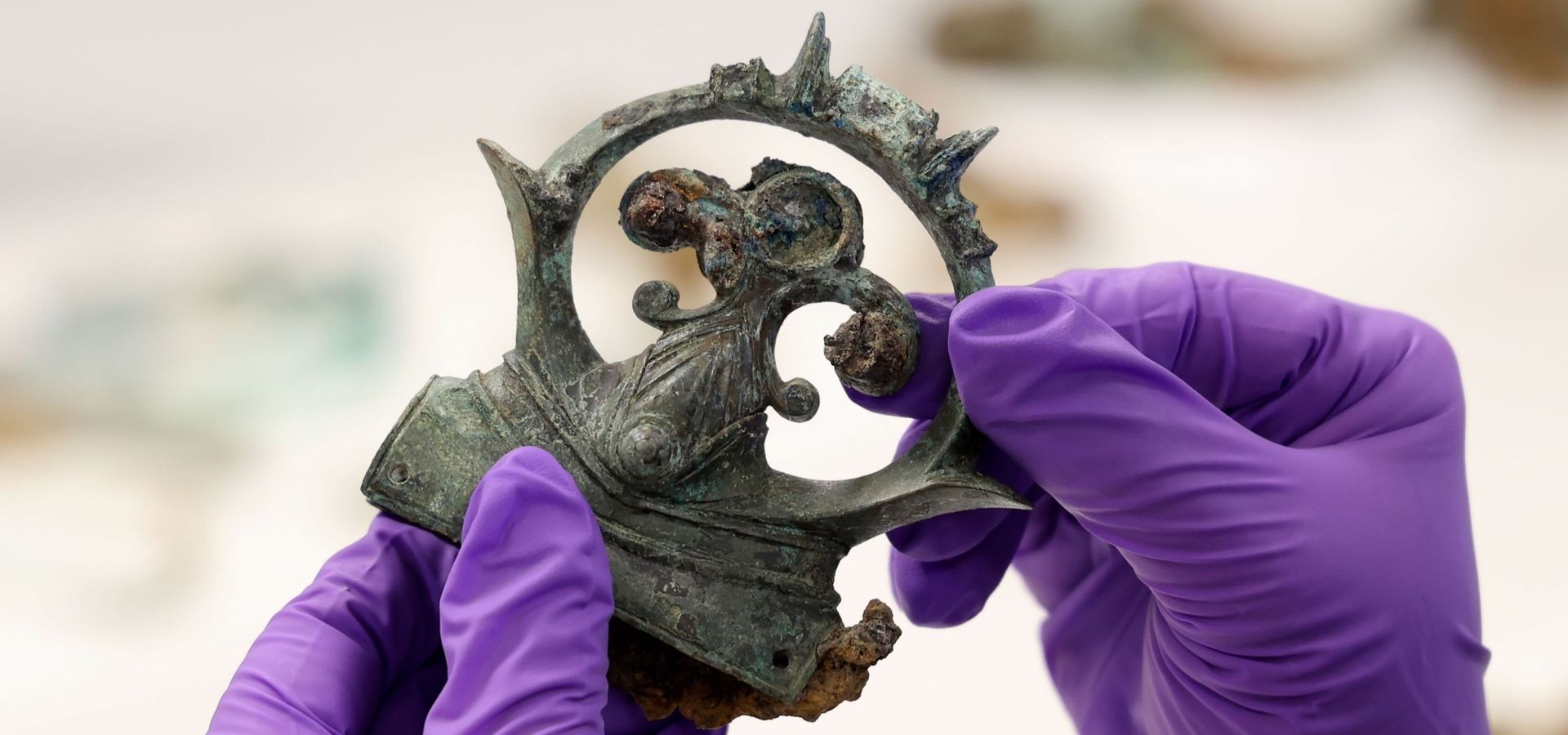gloved hands holding an ornate iron buckle