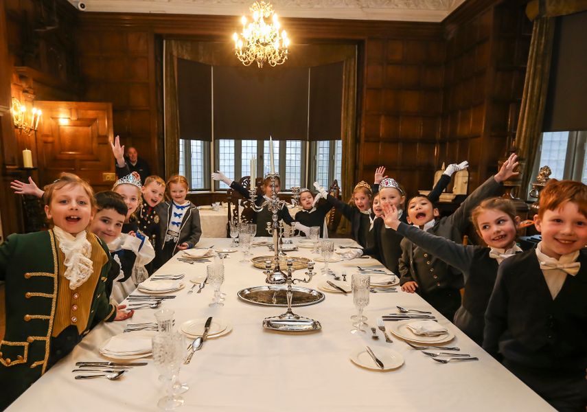 A group of students in victorian attire around a dressed table in Temple Newsam