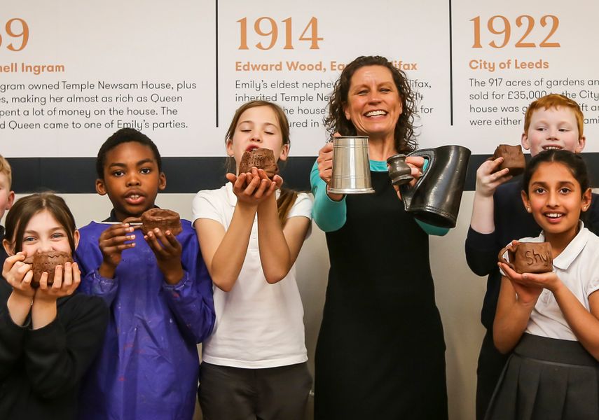 Students holding clay items they have made in a learning workshop