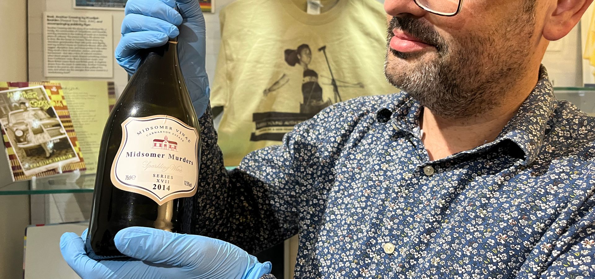 A curator holoding a wine bottle from 2014 called midsomer muders