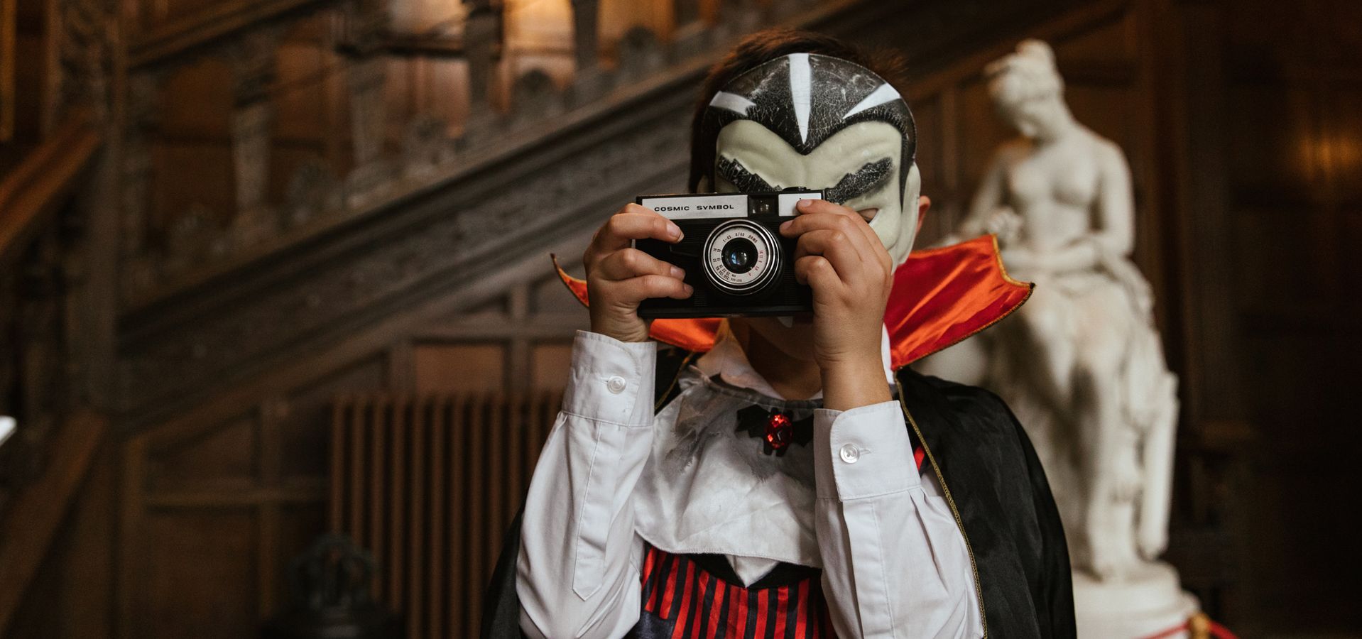 A child dressed as a vampire holdling a camera to their face