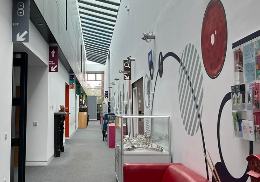 The main corridor in Leeds Discovery Centre, with a red sofa on the right and toilet signs on the left