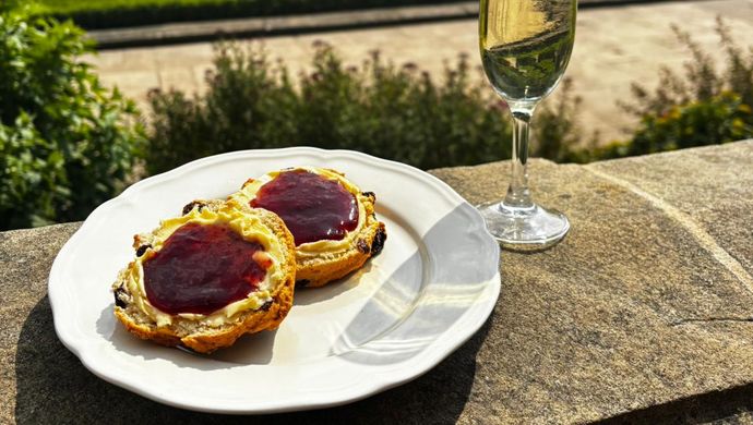 Scone with jam on a plate with a glass of prosecco on the terrace