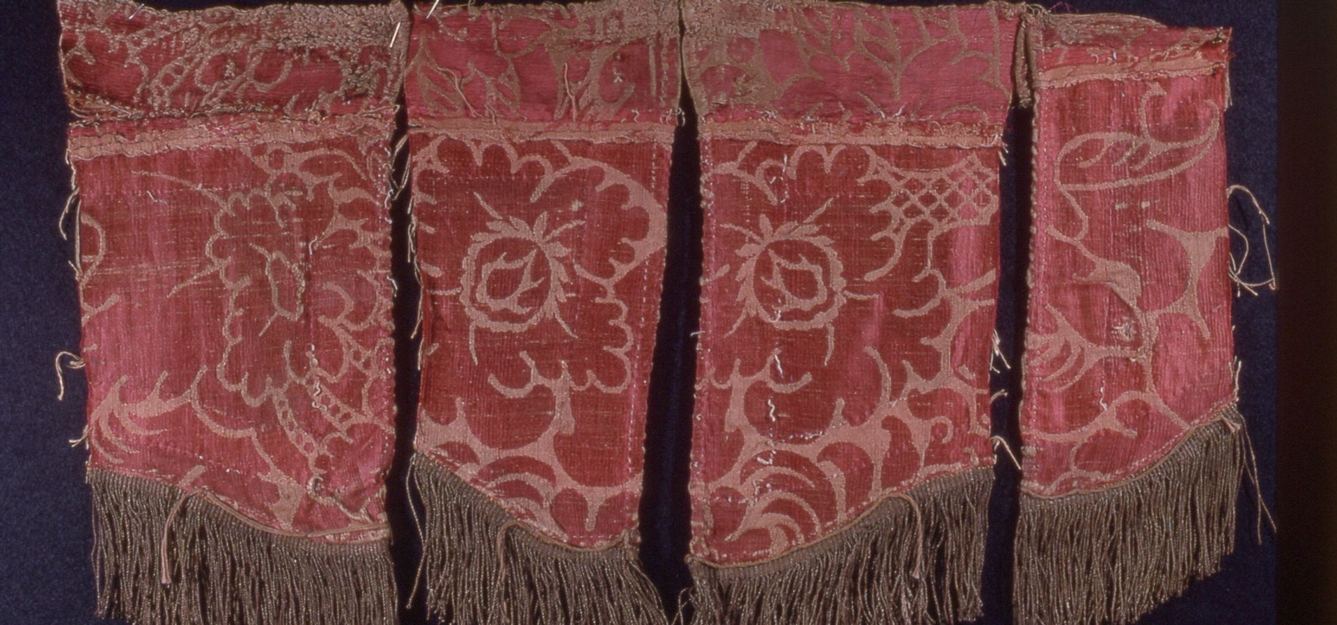 Examples of silk damsak from the Temple Newsam collection, 4 tuffs with tassels and red patterns