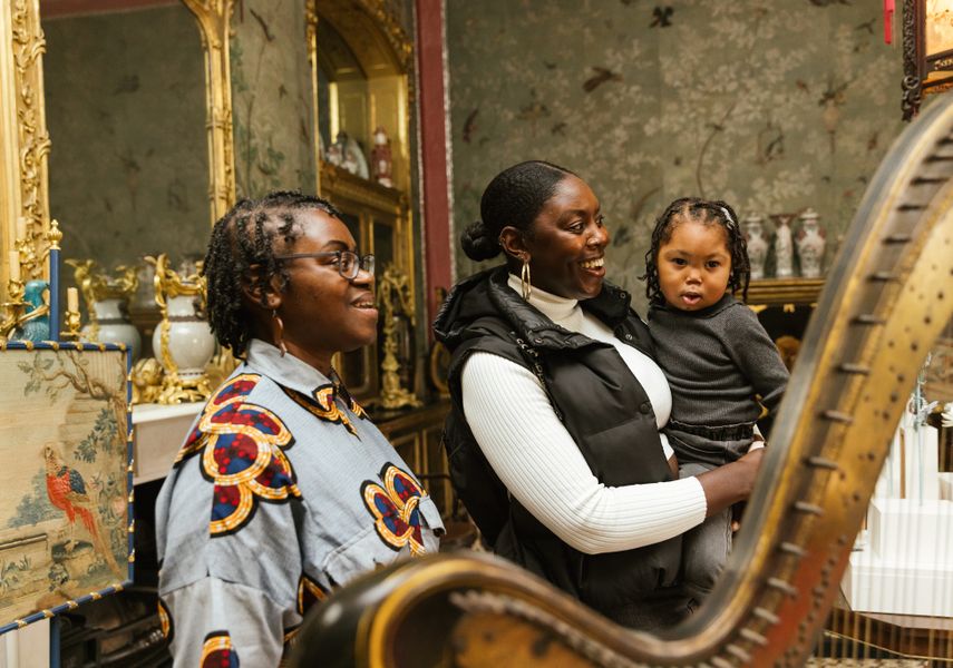 Two adults and a toddler looking at object in Temple Newsam House