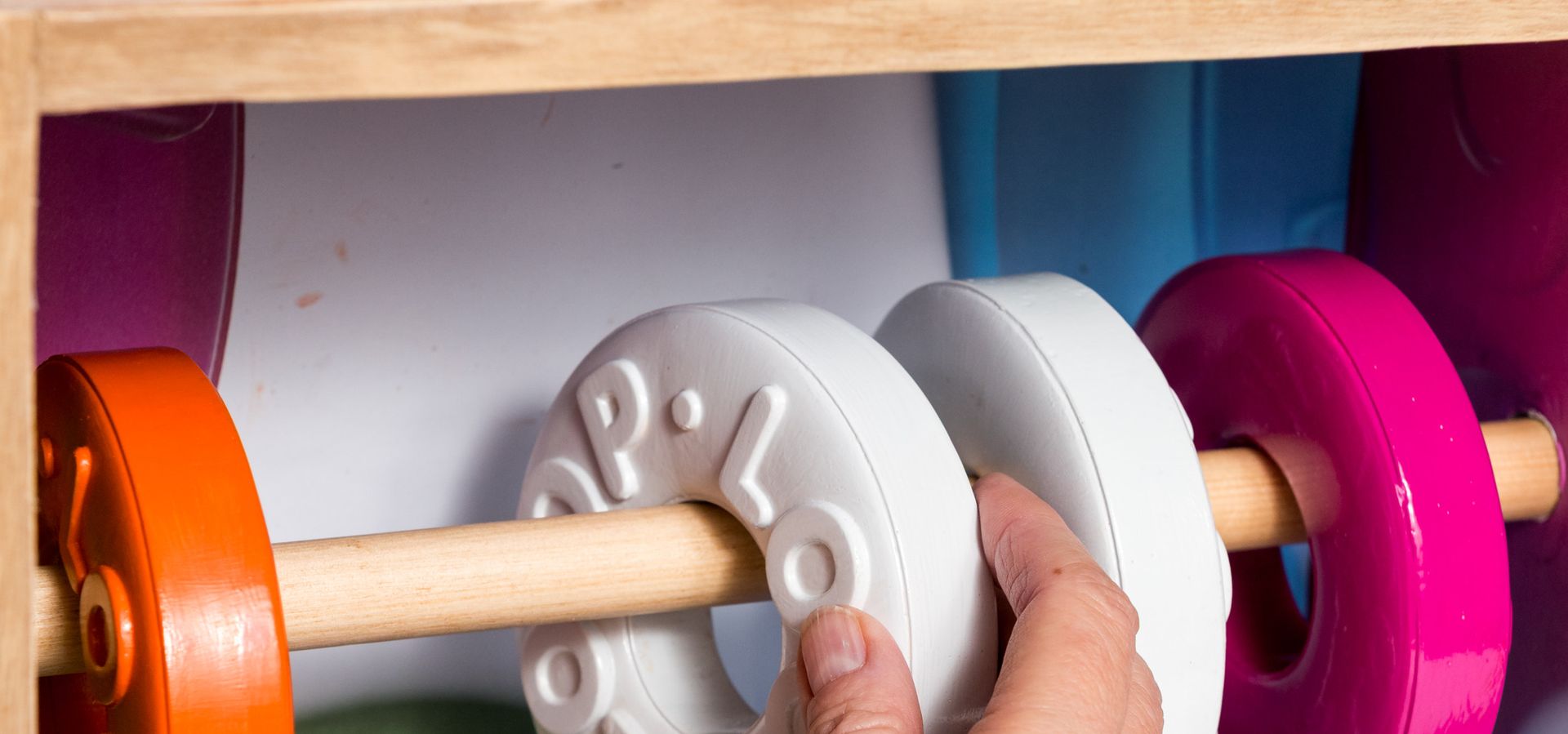 A hand moving rings on a wooden beam