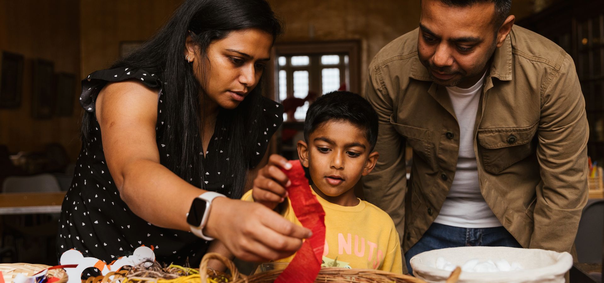 Two parents and a child pulling out craft materials