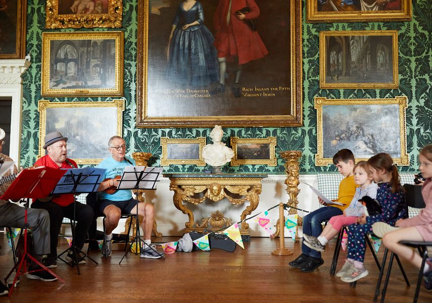 Musicians play music to seated children inside Temple Newsam.