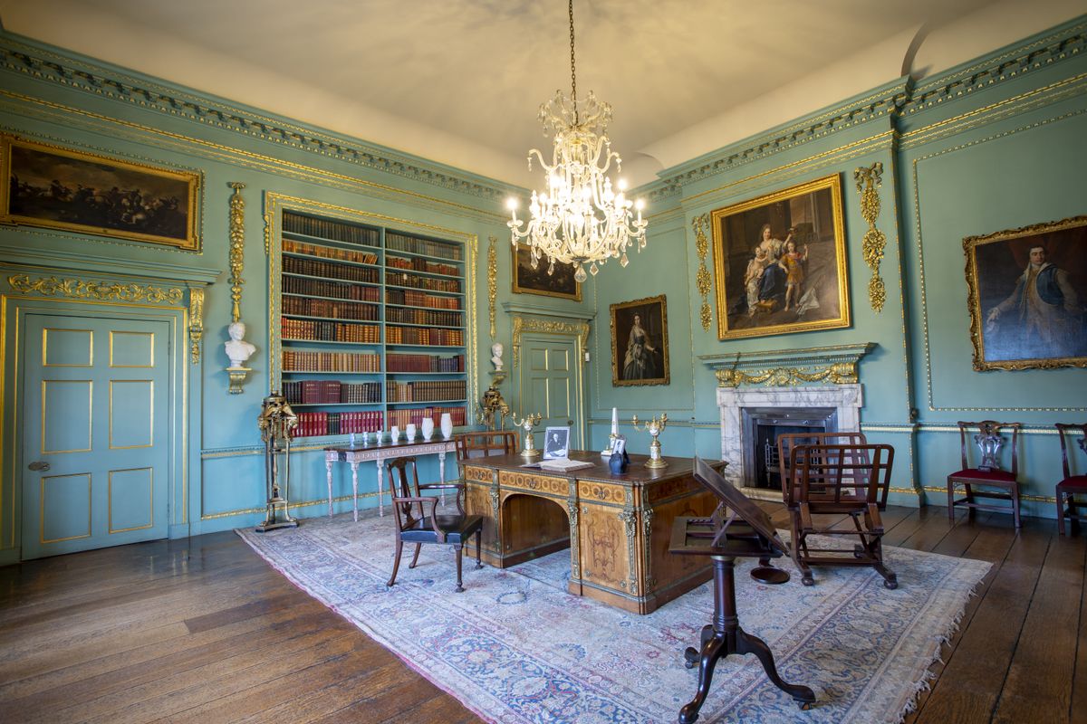 A turquoise room in Temple Newsam with large bookshelves and a Chippendale desk in the middle