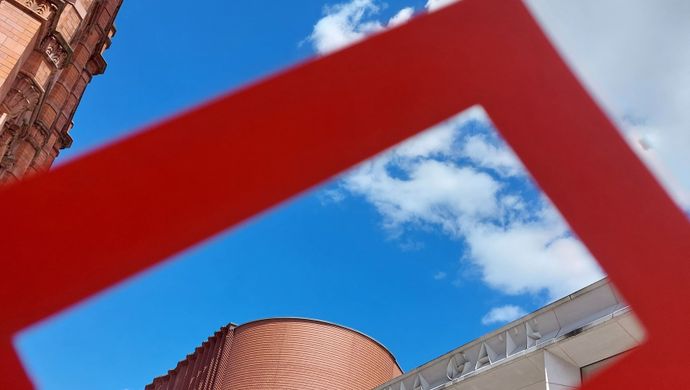 A red frame held up against the sky and the Victoria Gate sign in Leeds