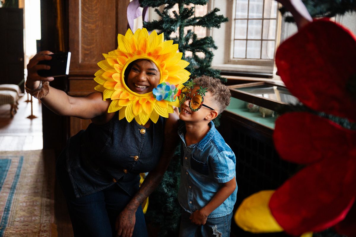 Child and adult posing together with props at a floral themed selfie arch