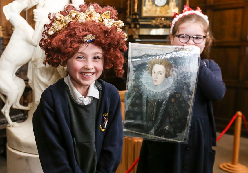 Two children, one dressed up as a Queen, and the other holding an image of Queen Elizabeth