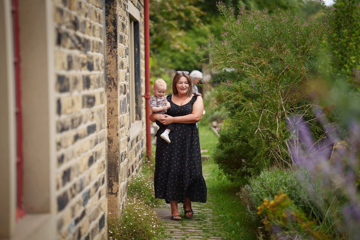 An adult carrying a toddler down a pathway next to a building