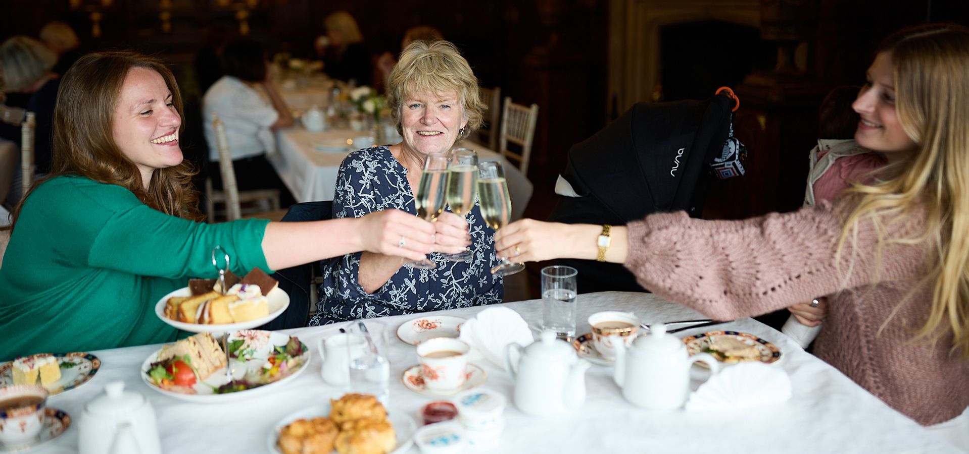 3 adults cheersing prosecco with afternoon tea at Temple Newsam