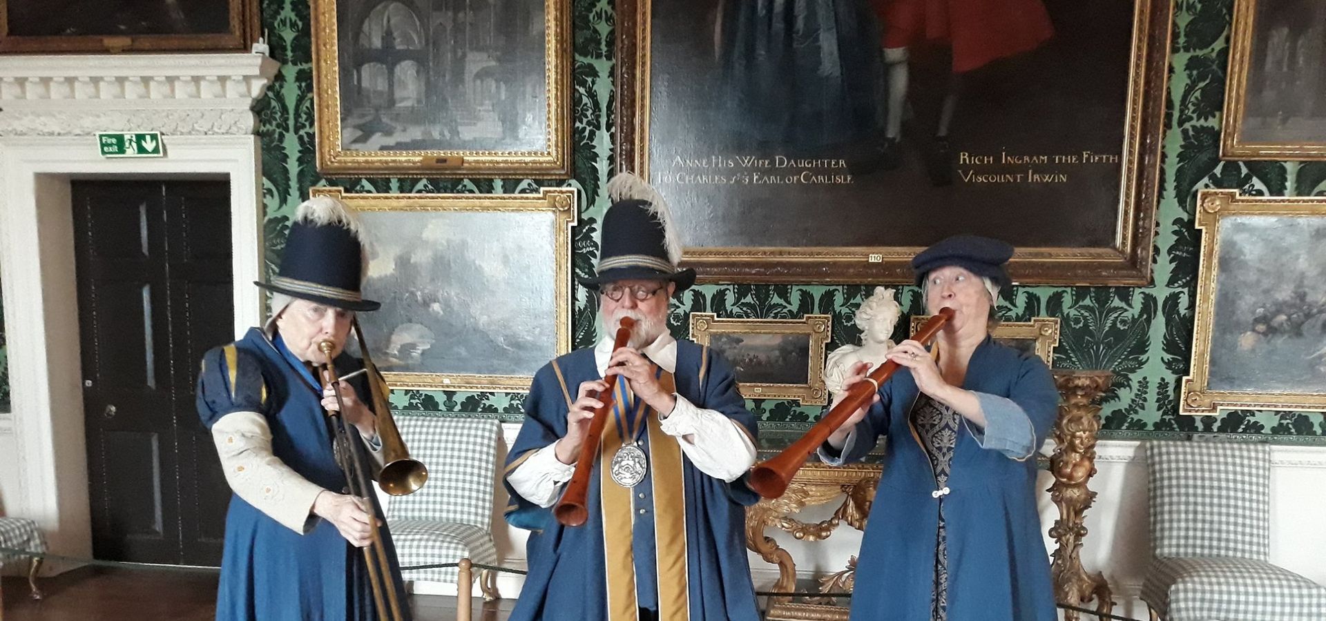 3 people dress in blue robes playing instruments in Temple Newsam