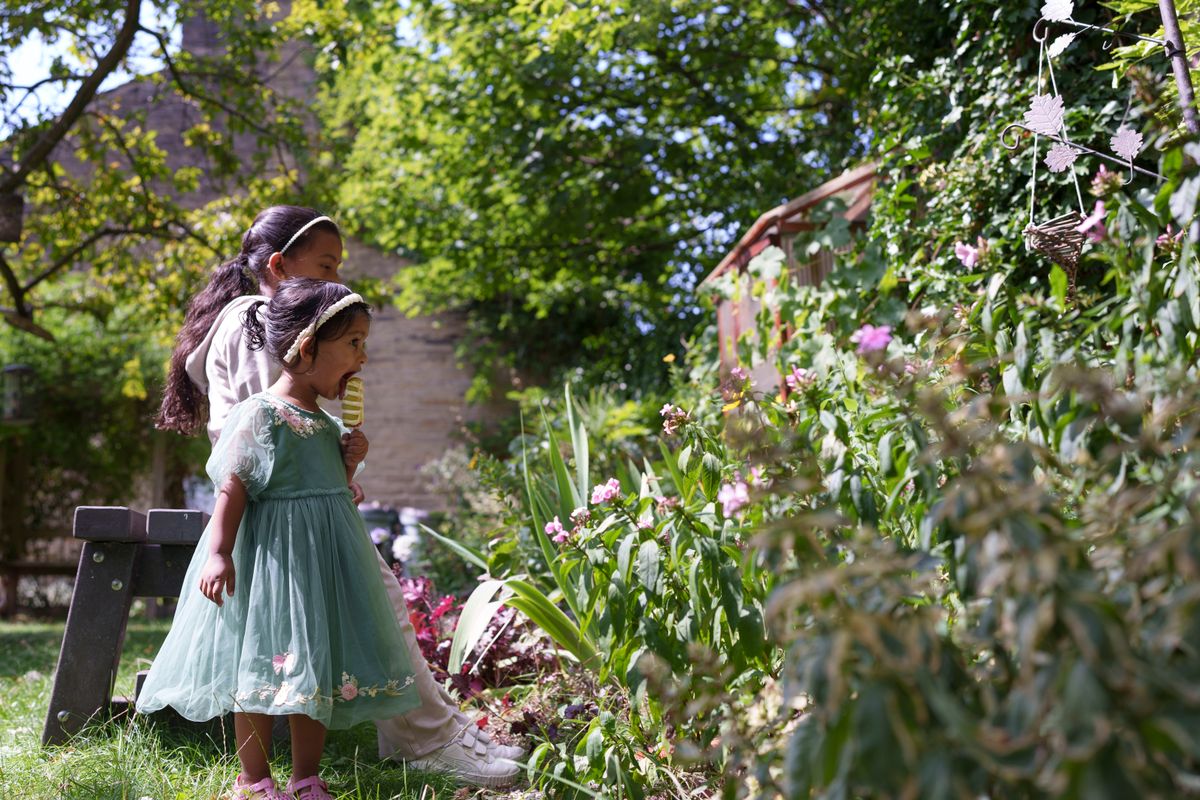 Two children eating ice cream looking into a flower bed