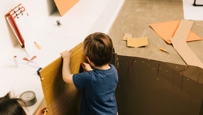 A toddler playing with cardboard and crafting materials