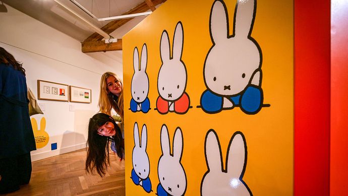 Two heads poking around the side of a large miffy book